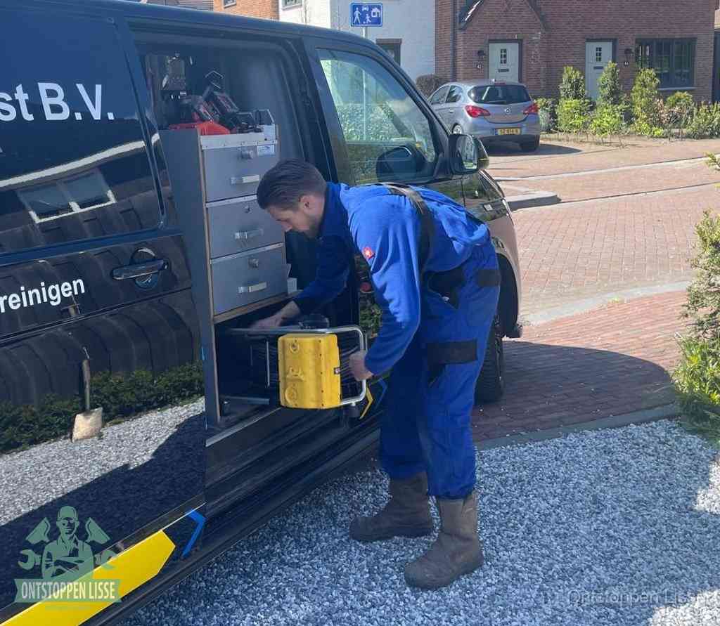 Een monteur pakt buiten op de oprit gereedschap uit de bedrijfsbus, het moment om een professional in te schakelen voor een verstopte afvoer in Lisse