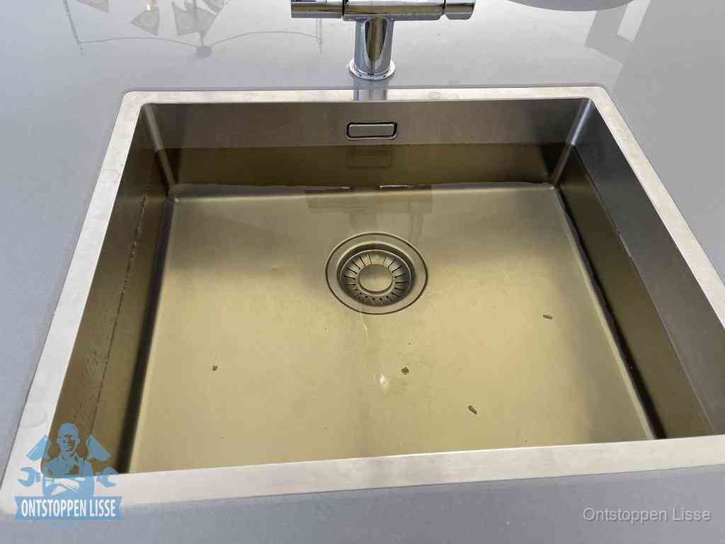 Stilstaand water in een rvs spoelbak dat niet wegloopt, een duidelijk signaal van een gootsteenverstopping in Lisse