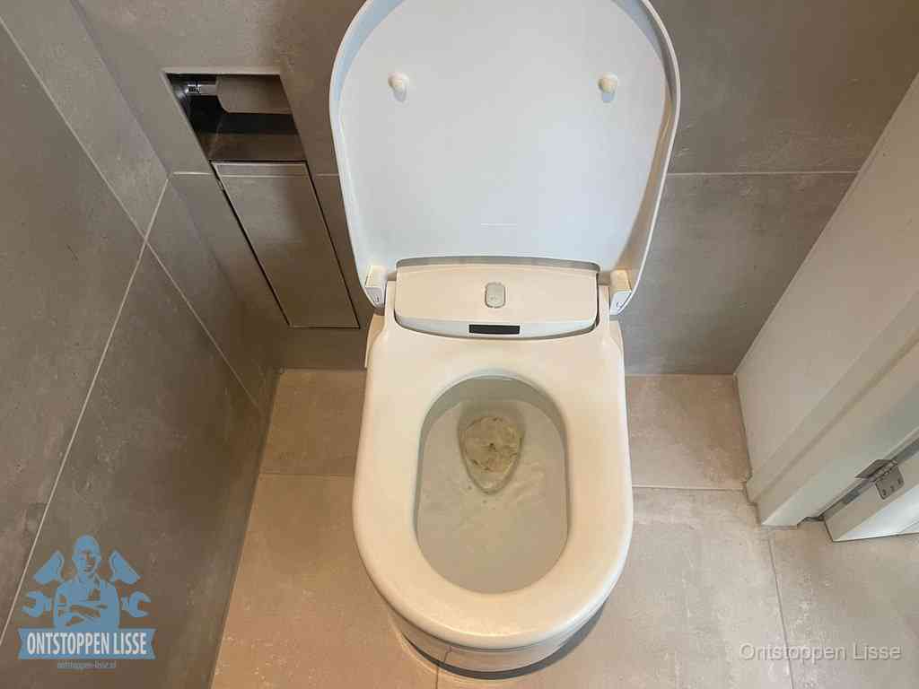 Een wit hangtoilet waarin een prop wc-papier op het water blijft drijven, een duidelijk signaal van een verstopte wc in Lisse