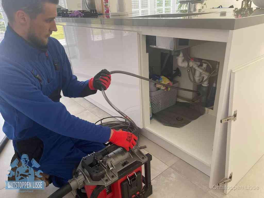 Een monteur reinigt de keukenafvoer grondig met een veermachine om terugkerende gootsteenverstoppingen te voorkomen in Lisse